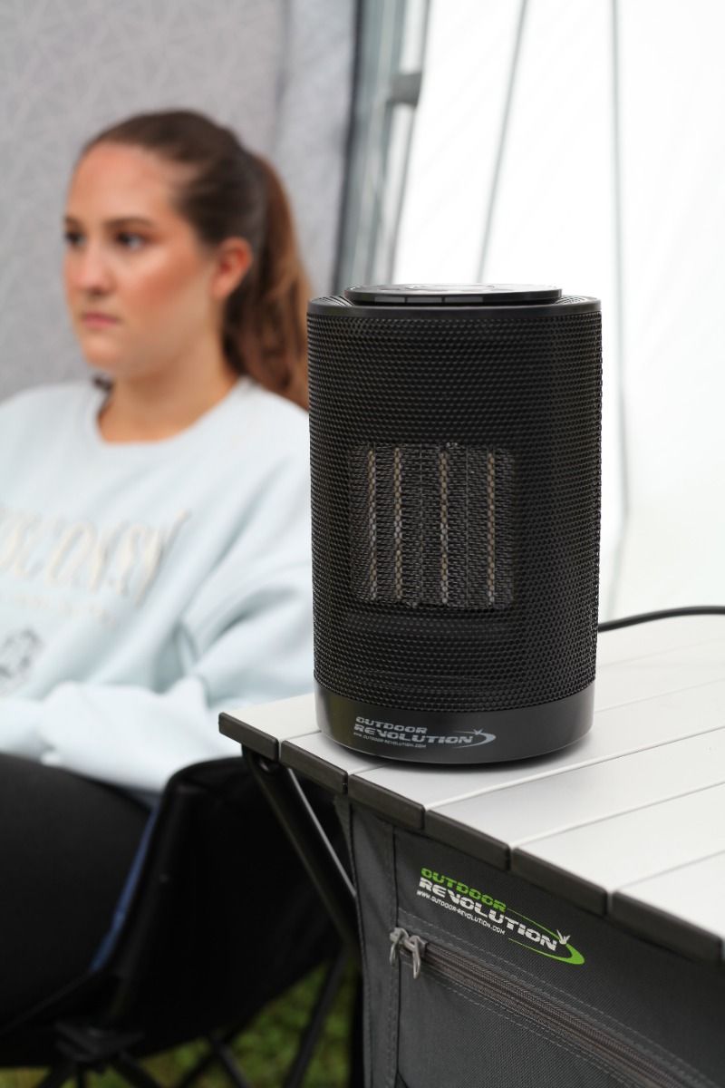 Black portable heater on a table with a person sitting in the background